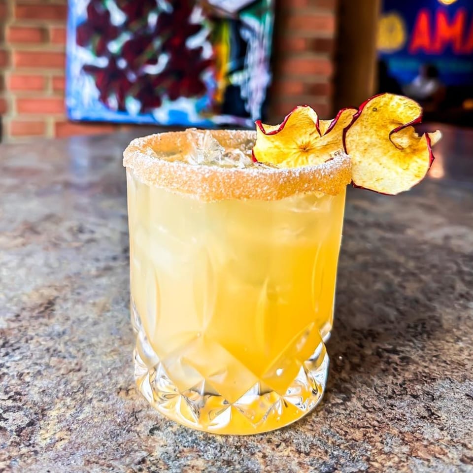 Amaya's Fresh Mexican Grill's margarita, garnished with dried apple slices, on a stone bar.