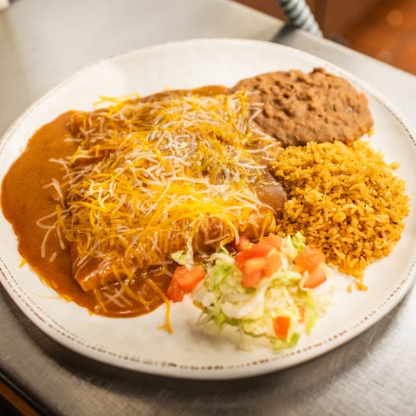 Amaya's enchiladas covered in red sauce and cheese, with a side of rice, beans, and salad.