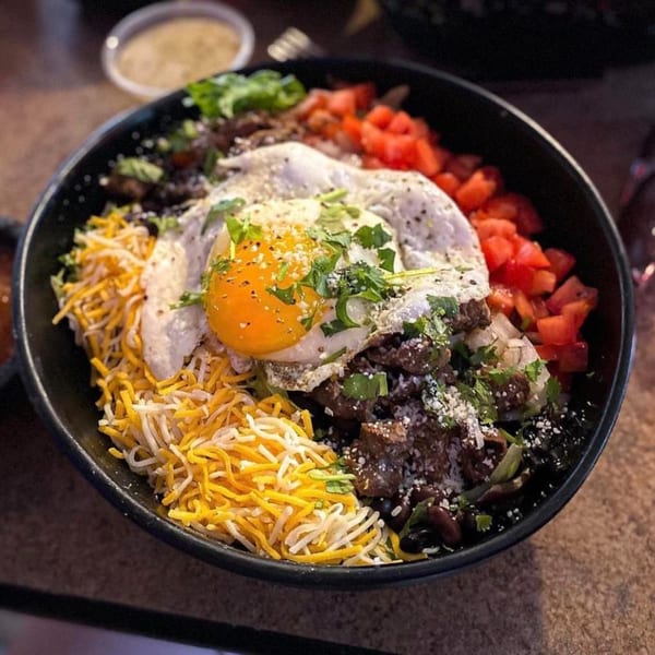 Amaya's Fresh Mexican Grill's breakfast bowl with a fried egg, cheese, tomatoes, and meat.