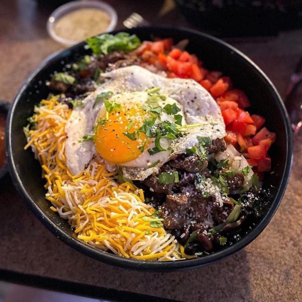 Amaya's Fresh Mexican Grill's breakfast bowl with a fried egg, cheese, tomatoes, and meat.