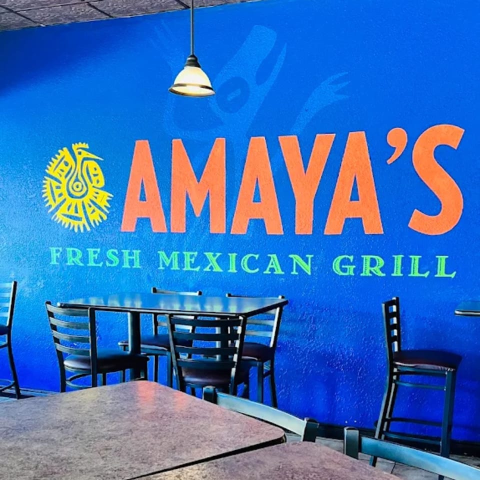 Amaya's Fresh Mexican Grill logo in orange and green on a vibrant blue wall above dining tables.