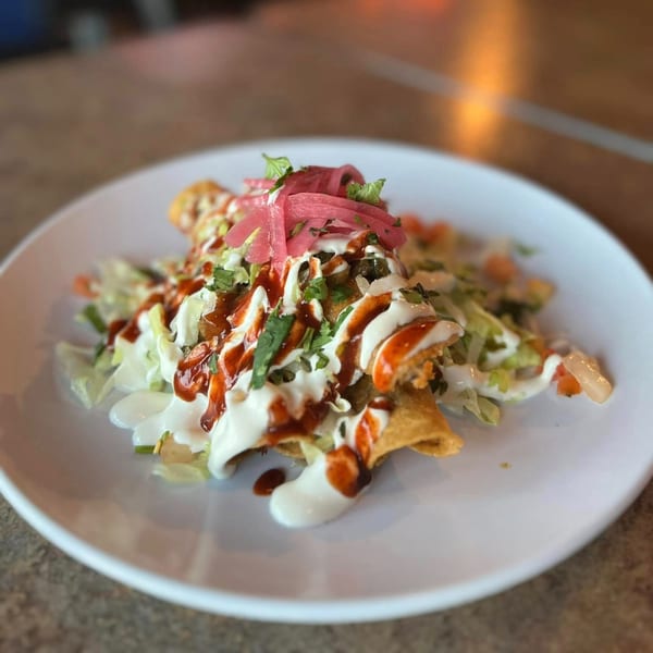 Amaya's Fresh Mexican Grill's taquitos topped with lettuce, sour cream, red sauce, and pickled red onions.