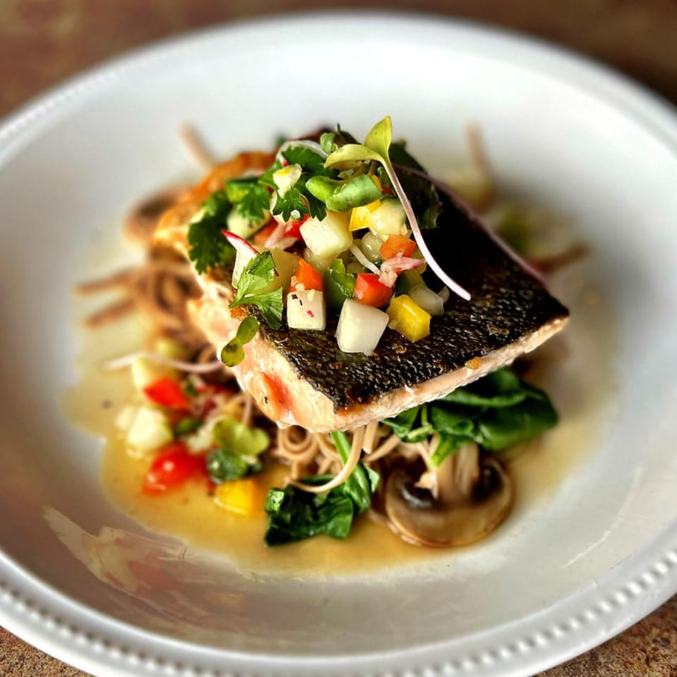 Crispy-skinned salmon with colorful salsa, noodles, spinach, and mushrooms in a light broth.
