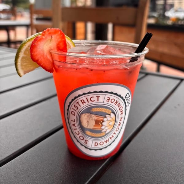 Strawberry margarita with lime and strawberry slices, on a dark outdoor table at Amaya's Fresh Mexican Grill.