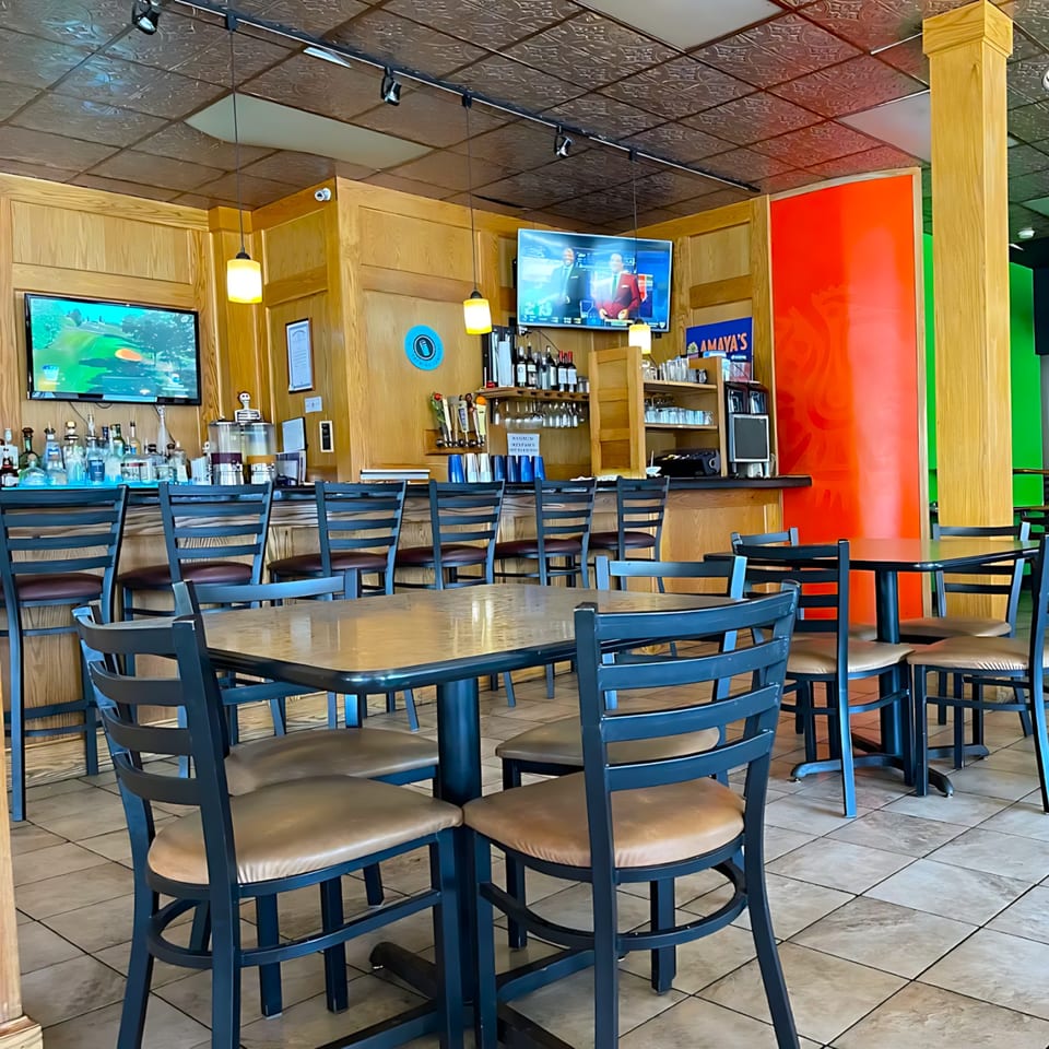 Interior of Amaya's Fresh Mexican Grill, showing empty dining tables, chairs, and a full bar area.